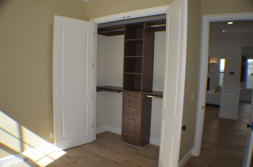 Diseño de armario unisex clásico pequeño con armarios estilo shaker, puertas de armario de madera en tonos medios, suelo de madera clara y suelo marrón