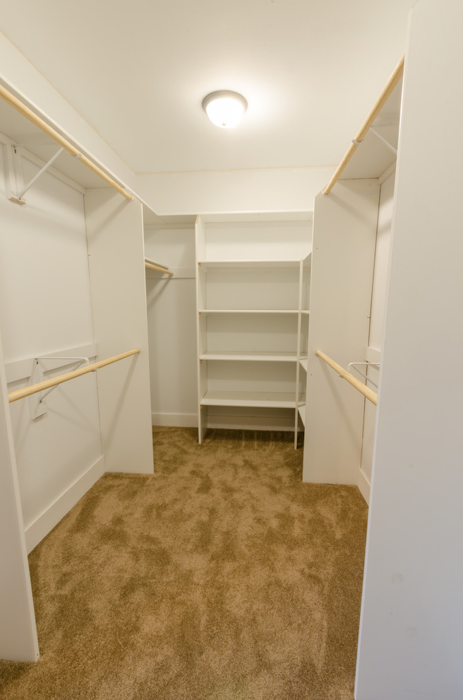 Large farmhouse gender neutral walk-in wardrobe in Milwaukee with carpet and beige floors.