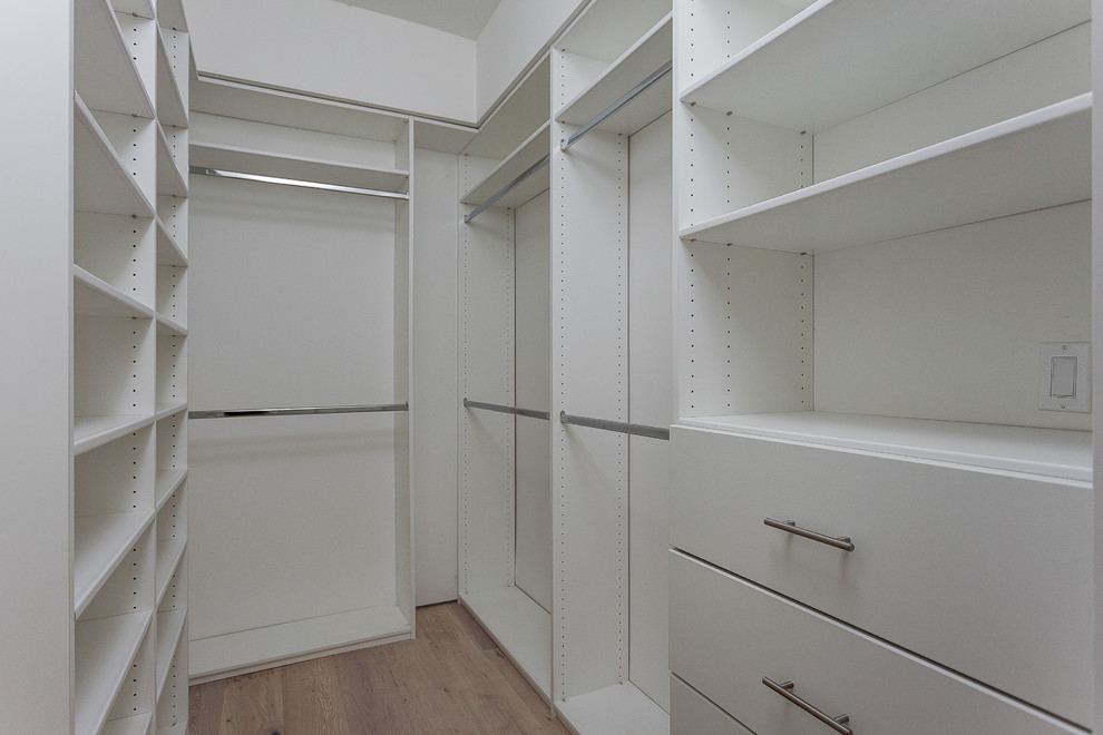 Esempio di una cabina armadio tradizionale di medie dimensioni con ante lisce, ante bianche e parquet chiaro