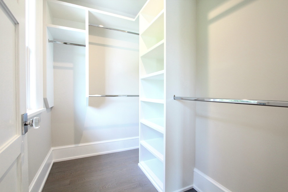 Diseño de armario vestidor unisex actual pequeño con armarios abiertos, puertas de armario blancas, suelo de madera en tonos medios y suelo marrón