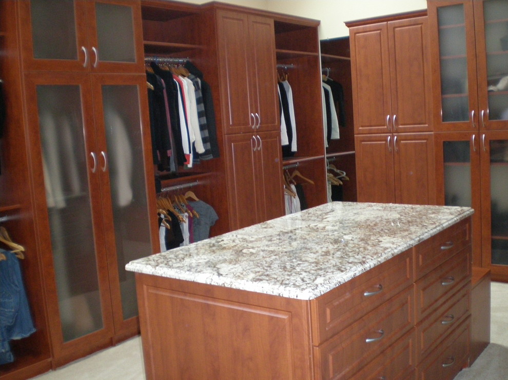 Diseño de armario vestidor unisex tradicional grande con armarios con paneles con relieve, puertas de armario de madera oscura, moqueta y suelo beige
