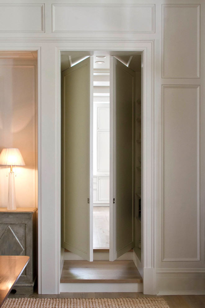 Aménagement d'un dressing classique de taille moyenne et neutre avec des portes de placard blanches, un sol en bois brun et un sol marron.