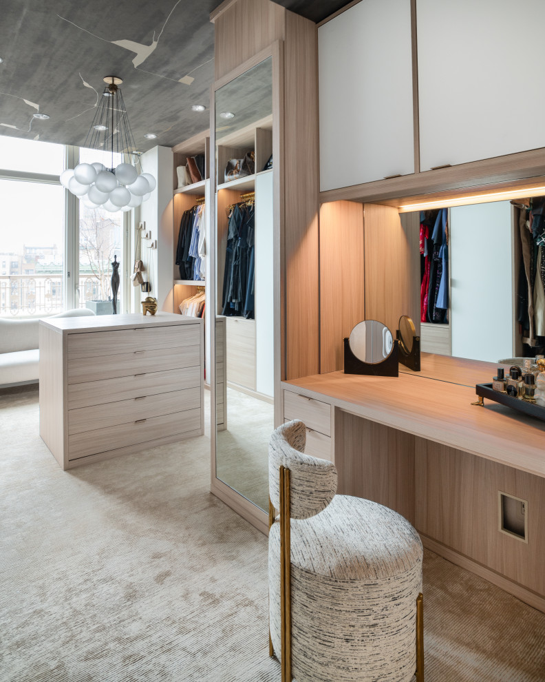 This is an example of an expansive contemporary dressing room for women in New York with flat-panel cabinets, light wood cabinets, carpet, beige floors and a wallpapered ceiling.