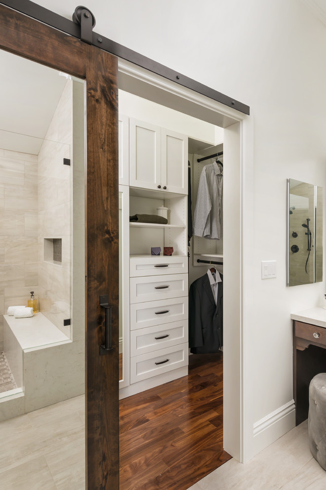 Exemple d'un grand dressing room chic neutre avec un placard à porte shaker, des portes de placard blanches, un sol en bois brun et un sol marron.