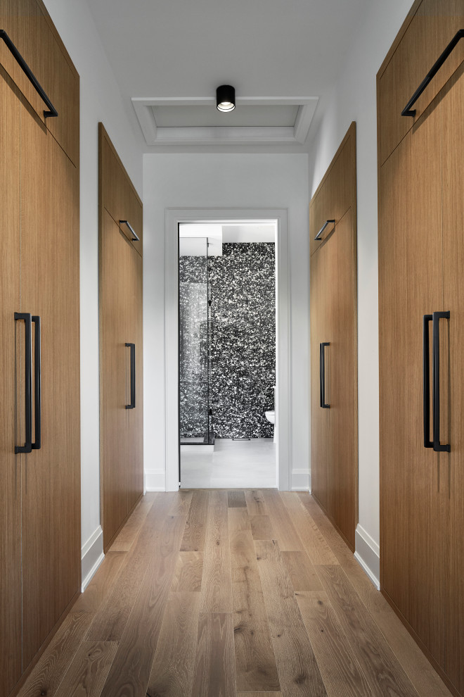 Aménagement d'une grande armoire encastrée contemporaine en bois clair neutre avec un placard à porte plane, parquet clair et un sol beige.