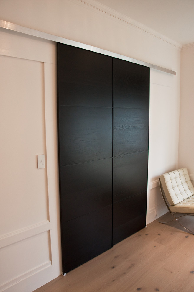 This is an example of a medium sized modern gender neutral walk-in wardrobe in San Francisco with light hardwood flooring.