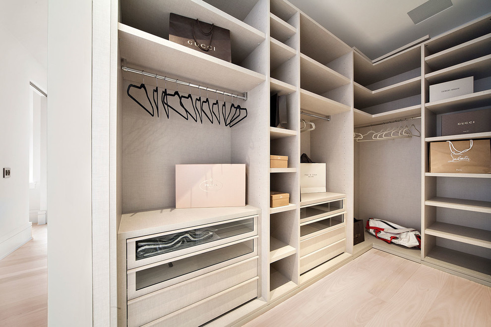 Example of a mid-sized trendy gender-neutral light wood floor and beige floor walk-in closet design in New York with flat-panel cabinets and distressed cabinets