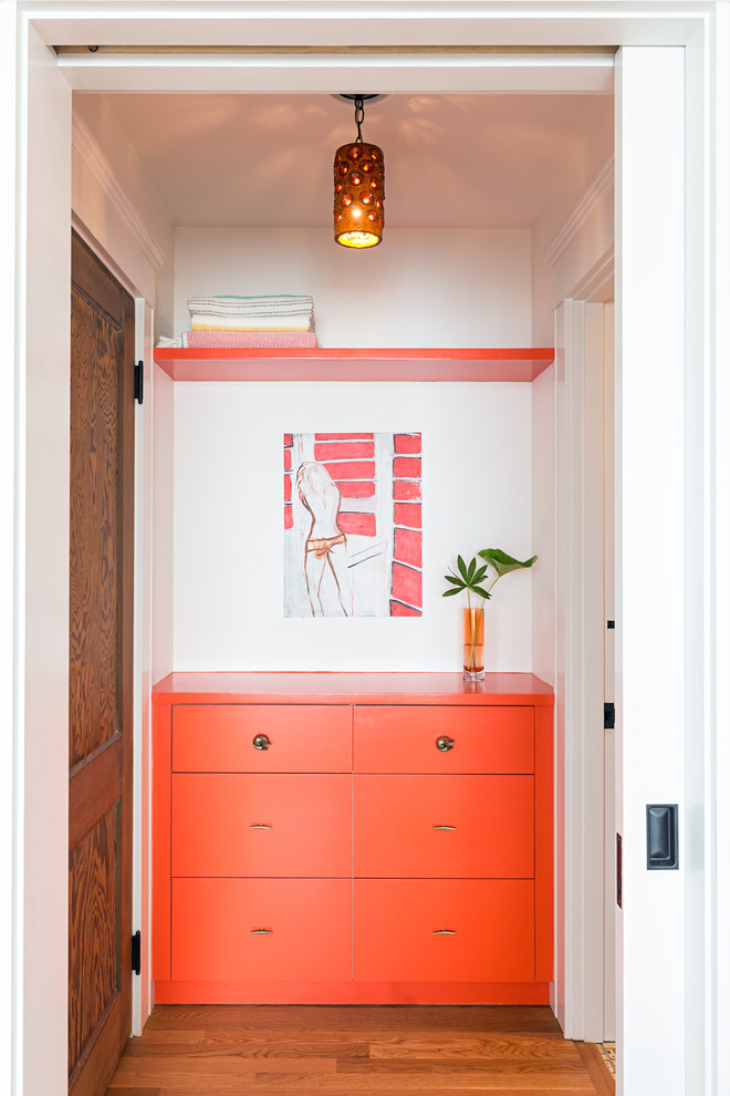 Imagen de armario y vestidor contemporáneo con suelo de madera en tonos medios, armarios con paneles lisos y puertas de armario naranjas