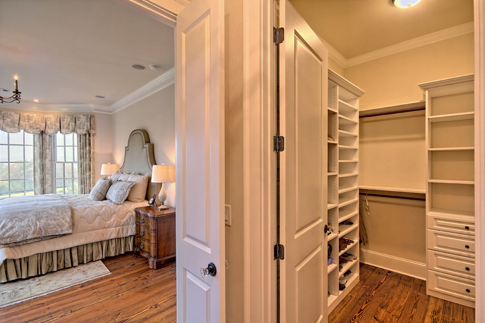 Imagen de armario vestidor unisex clásico de tamaño medio con armarios con paneles con relieve, puertas de armario blancas y suelo de madera en tonos medios