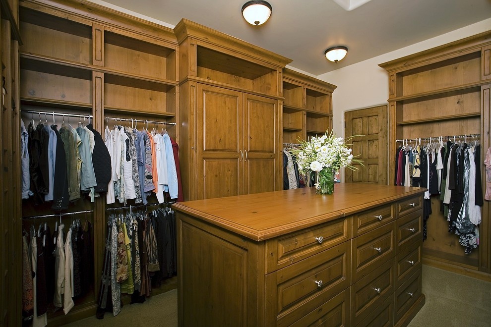 Diseño de armario vestidor unisex clásico grande con armarios con paneles con relieve, puertas de armario de madera oscura y moqueta