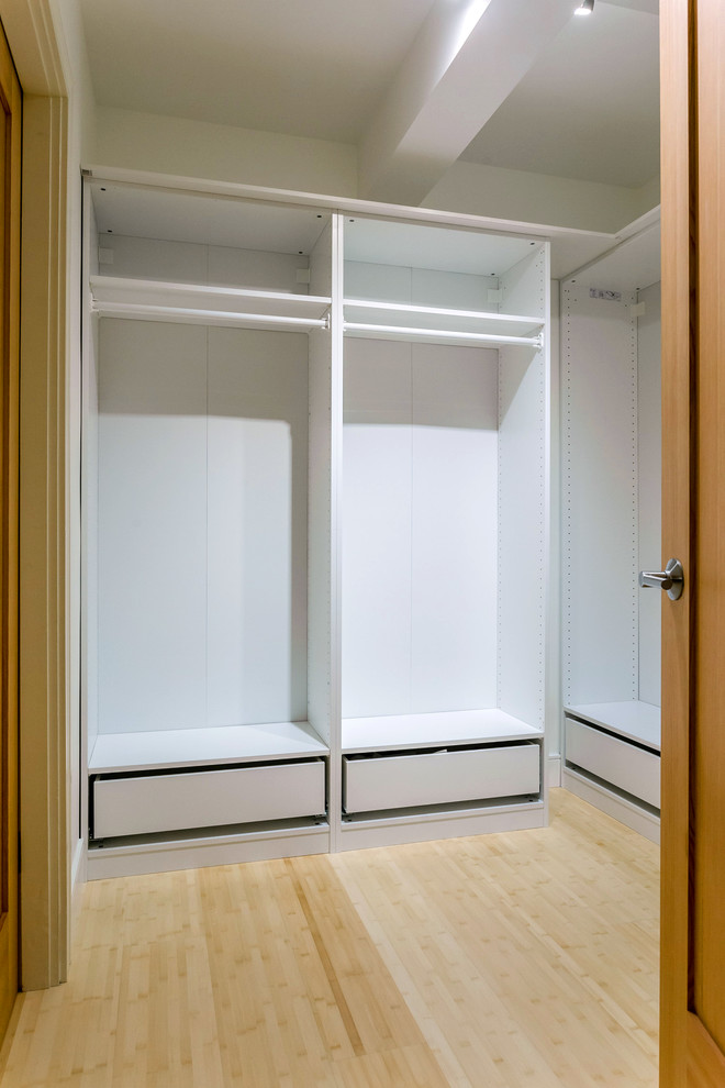 Amerikansk inredning av ett stort walk-in-closet för könsneutrala, med vita skåp och bambugolv