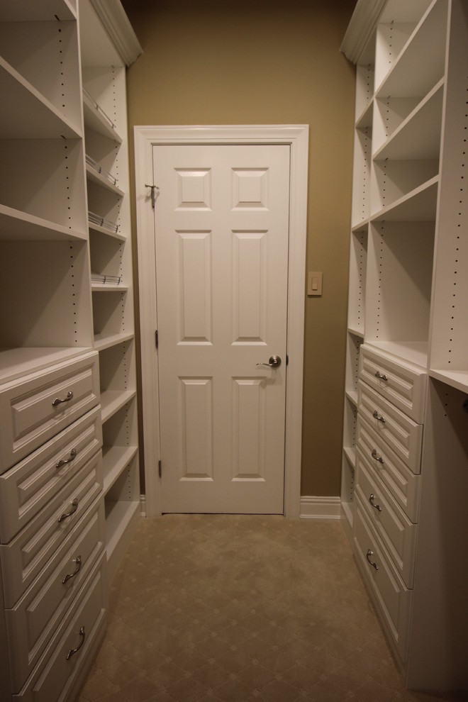 This is an example of a large classic walk-in wardrobe for women in Other with raised-panel cabinets, white cabinets and carpet.