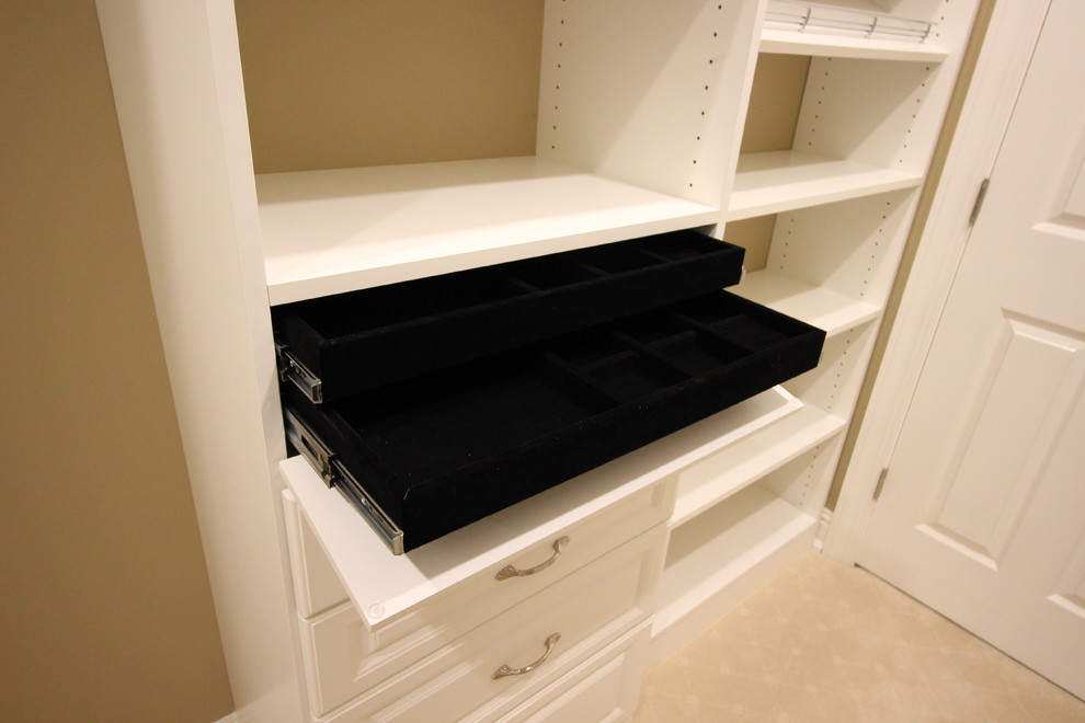 This is an example of a large classic walk-in wardrobe for women in Other with raised-panel cabinets, white cabinets and carpet.