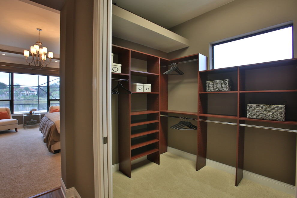 На фото: гардеробная комната унисекс в стиле фьюжн с темными деревянными фасадами и ковровым покрытием