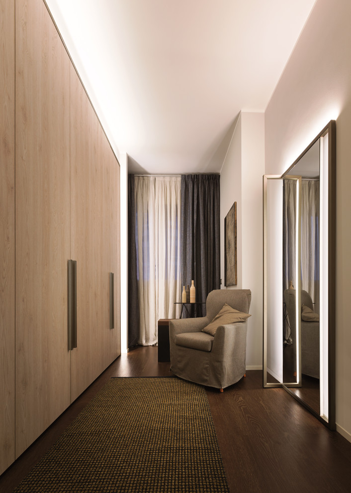 Neutrales Modernes Ankleidezimmer mit hellen Holzschränken, Ankleidebereich, flächenbündigen Schrankfronten und dunklem Holzboden in Mailand