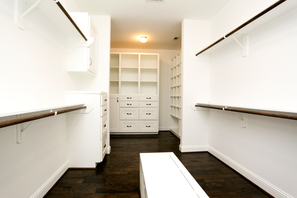 Diseño de armario vestidor unisex tradicional de tamaño medio con puertas de armario blancas, suelo de madera oscura y armarios con paneles empotrados