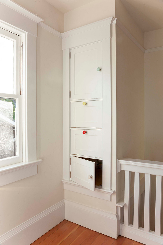 Cette photo montre un grand placard dressing craftsman neutre avec parquet clair, un placard à porte shaker et des portes de placard blanches.
