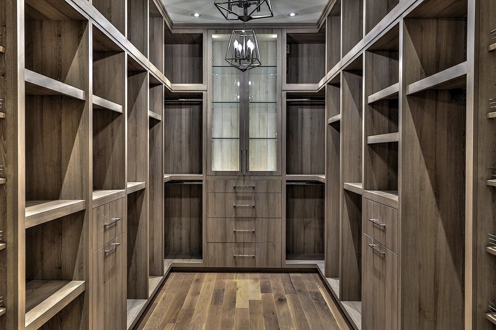 Minimalistisk inredning av ett stort walk-in-closet för könsneutrala, med släta luckor, skåp i mörkt trä, mörkt trägolv och brunt golv