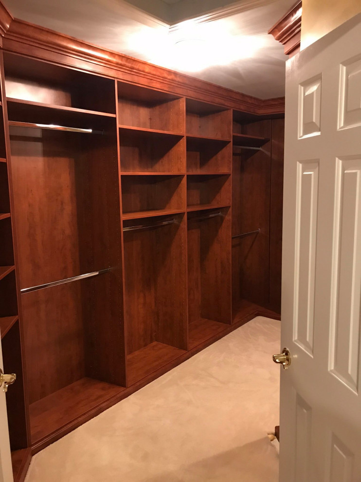 Photo of a large traditional gender neutral walk-in wardrobe in DC Metro with medium wood cabinets.