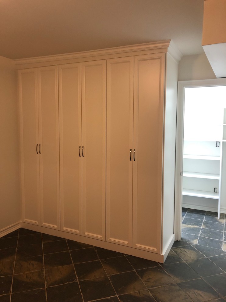 Cette image montre un placard dressing traditionnel de taille moyenne et neutre avec un placard avec porte à panneau encastré, des portes de placard blanches, un sol en ardoise et un sol noir.