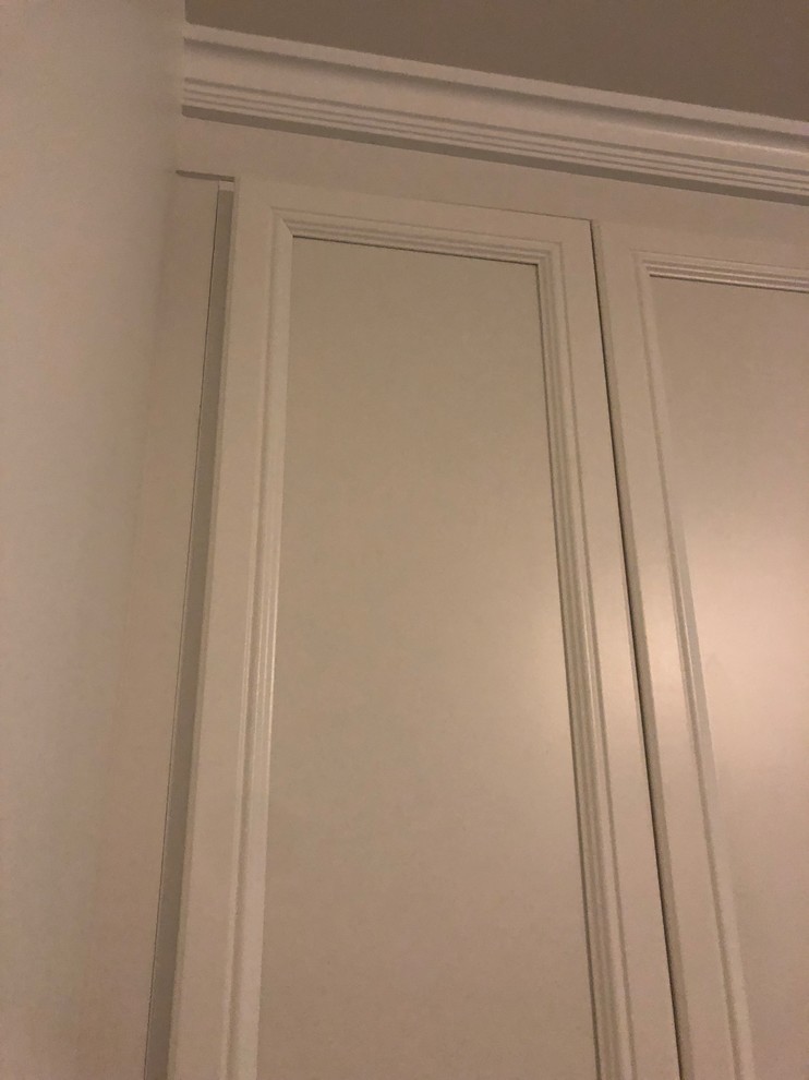 Cette image montre un placard dressing traditionnel de taille moyenne et neutre avec un placard avec porte à panneau encastré, des portes de placard blanches, un sol en ardoise et un sol noir.