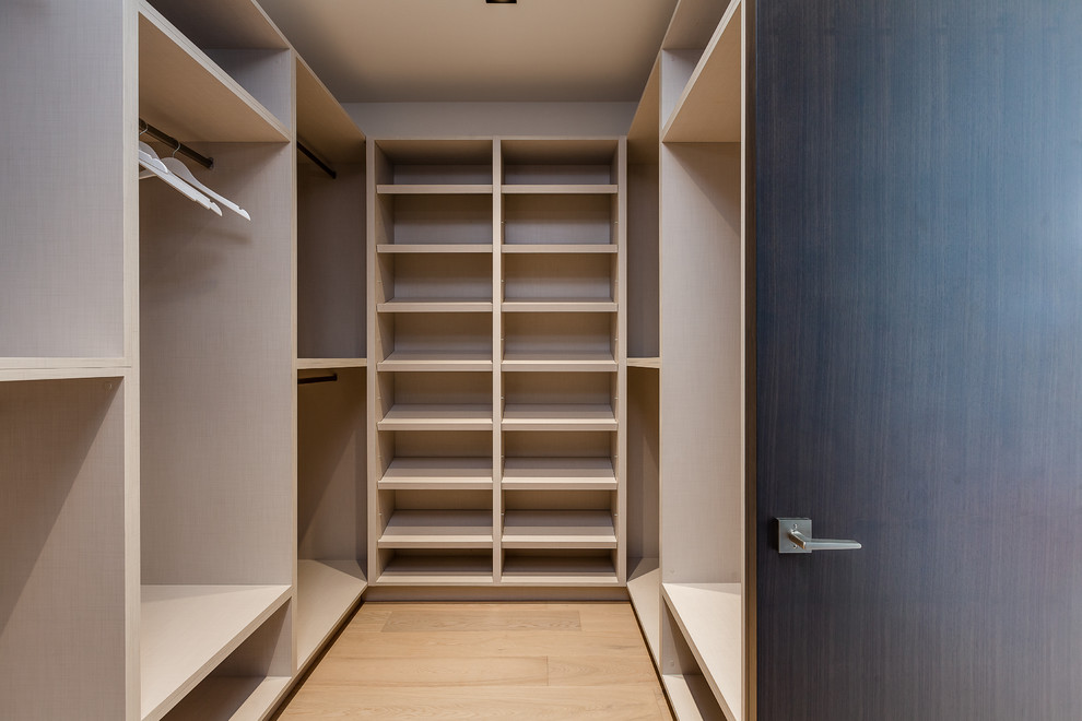Ispirazione per una cabina armadio unisex design di medie dimensioni con ante in legno chiaro, pavimento in legno massello medio e pavimento marrone