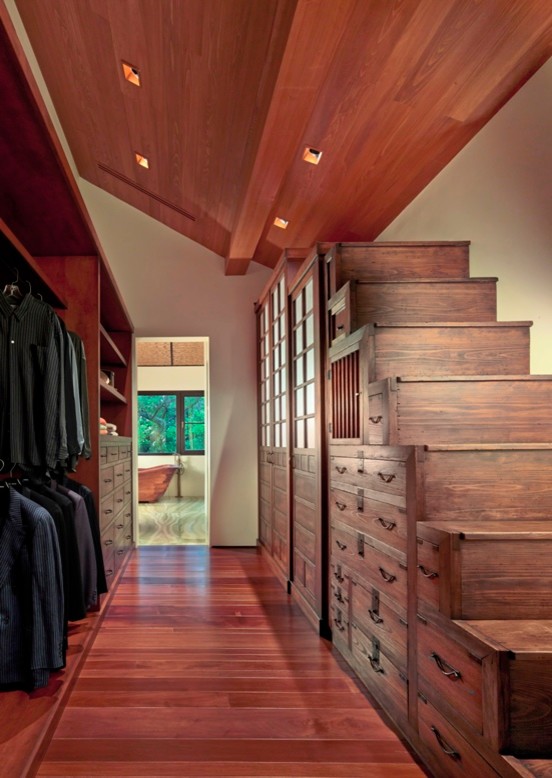 Diseño de armario vestidor de hombre de estilo zen grande con armarios con paneles lisos, puertas de armario de madera oscura y suelo de madera en tonos medios
