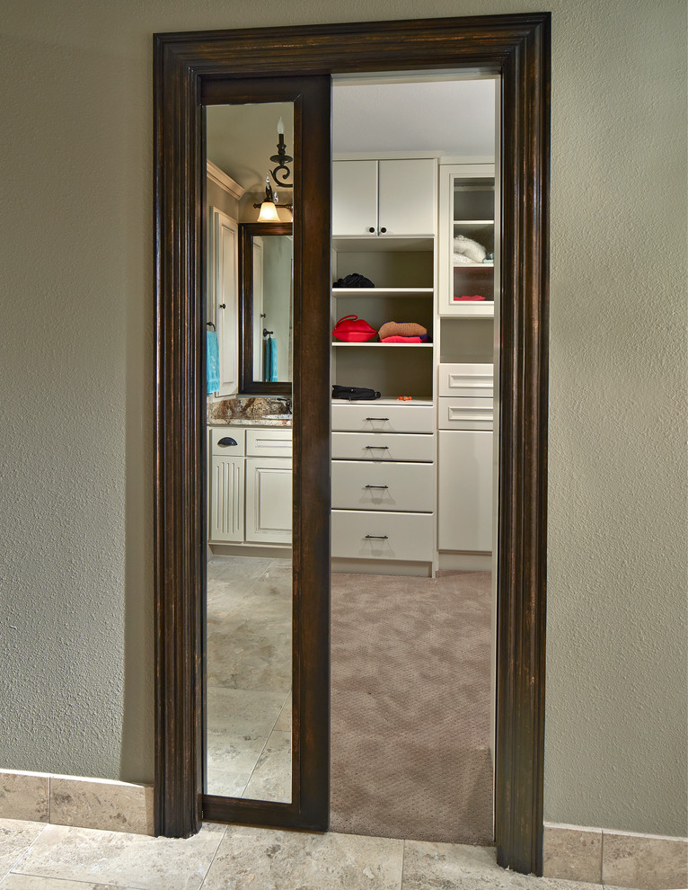Traditional gender neutral walk-in wardrobe in Dallas with white cabinets and carpet.