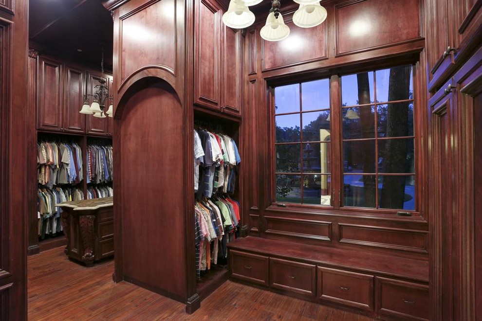 Aménagement d'un grand dressing room classique en bois brun pour un homme avec un placard avec porte à panneau encastré et un sol en bois brun.