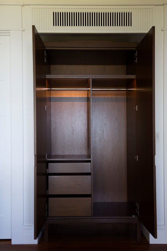 Foto di un piccolo armadio o armadio a muro unisex tropicale con ante lisce, ante in legno bruno, pavimento in legno massello medio e pavimento marrone