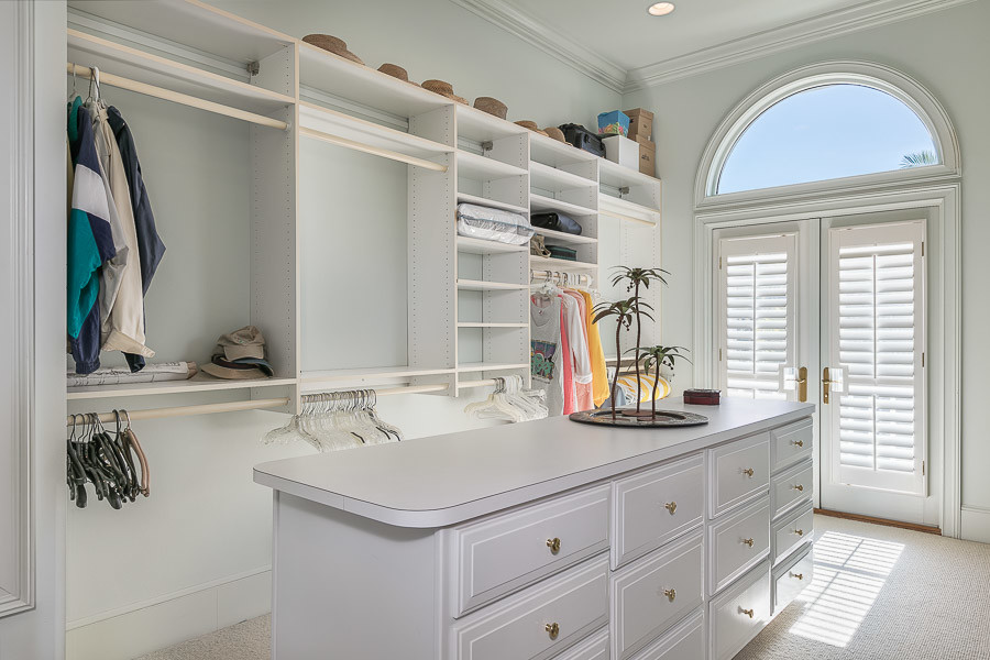 Inspiration for a large timeless gender-neutral carpeted walk-in closet remodel in Miami with flat-panel cabinets and white cabinets