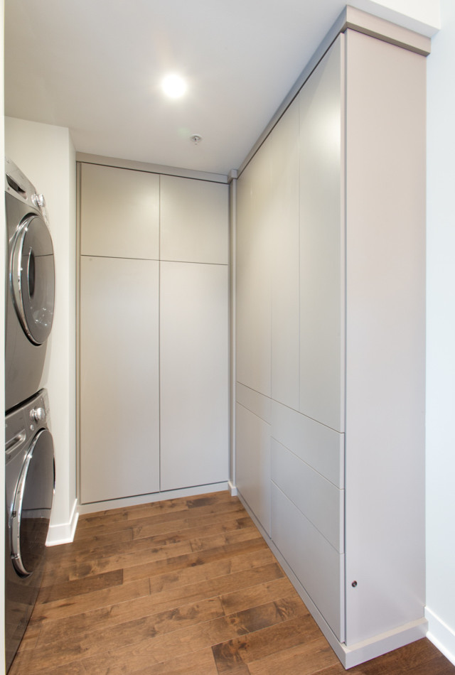 Foto de armario y vestidor unisex actual pequeño con armarios con paneles lisos, puertas de armario grises y suelo de madera en tonos medios