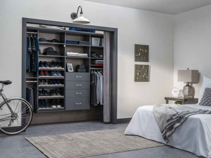 Diseño de armario unisex contemporáneo pequeño con puertas de armario grises, suelo de cemento y suelo beige