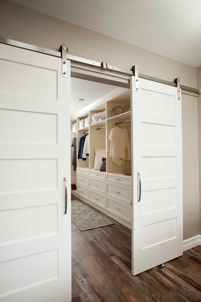 Design ideas for a large traditional gender neutral walk-in wardrobe in Calgary with open cabinets, white cabinets, medium hardwood flooring and brown floors.