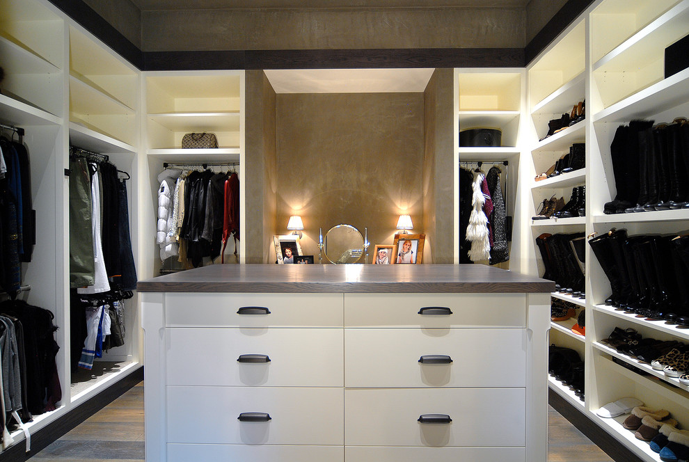 Imagen de armario vestidor unisex rural grande con armarios con paneles lisos, puertas de armario blancas, suelo de madera oscura y suelo marrón
