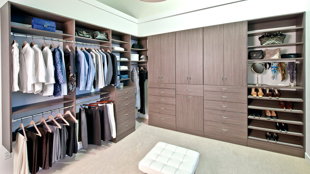 Foto de armario vestidor de hombre contemporáneo grande con armarios con paneles lisos, puertas de armario de madera oscura y moqueta