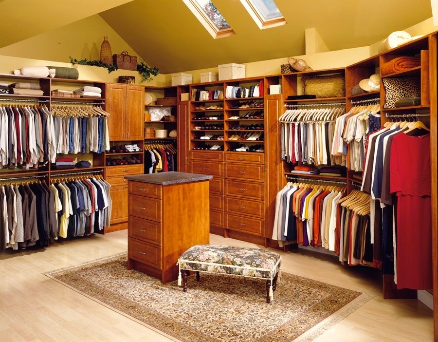 Imagen de armario vestidor unisex tradicional grande con armarios abiertos, puertas de armario de madera oscura, suelo de madera clara y suelo beige