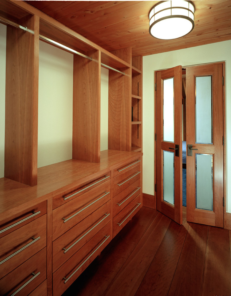 Example of a large arts and crafts gender-neutral dark wood floor and brown floor walk-in closet design in Sacramento with flat-panel cabinets and medium tone wood cabinets