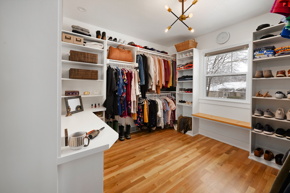 This is an example of a medium sized traditional gender neutral walk-in wardrobe in Kansas City with medium hardwood flooring, open cabinets, white cabinets and brown floors.
