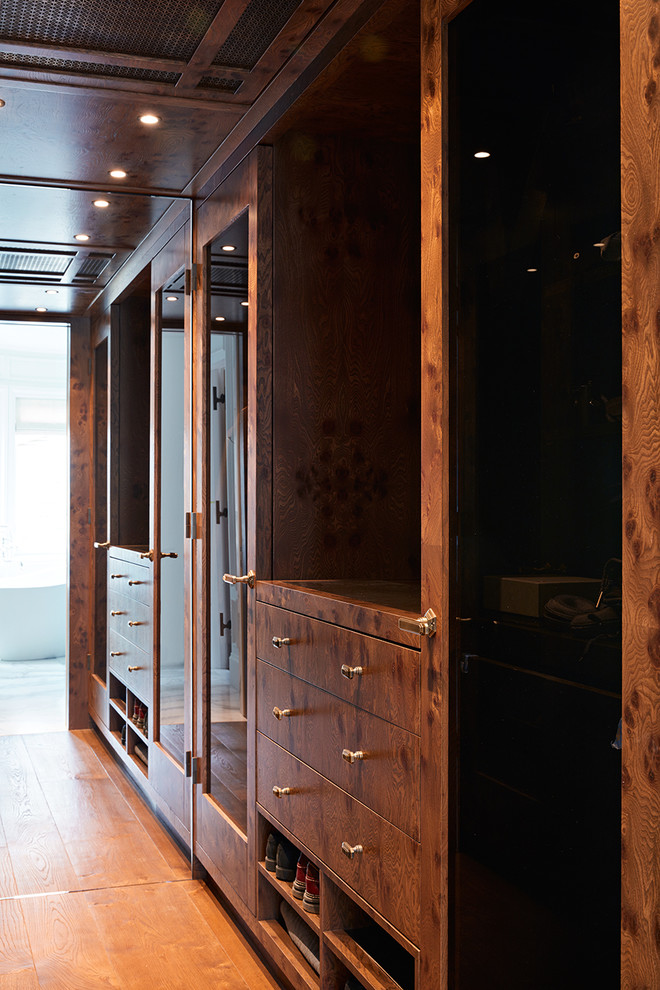Стильный дизайн: гардеробная комната в стиле неоклассика (современная классика) с плоскими фасадами, фасадами цвета дерева среднего тона, паркетным полом среднего тона, коричневым полом и деревянным потолком для мужчин - последний тренд