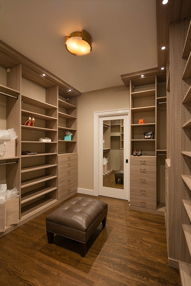 Cette image montre un dressing room traditionnel en bois clair neutre avec un placard à porte plane, parquet foncé et un sol marron.