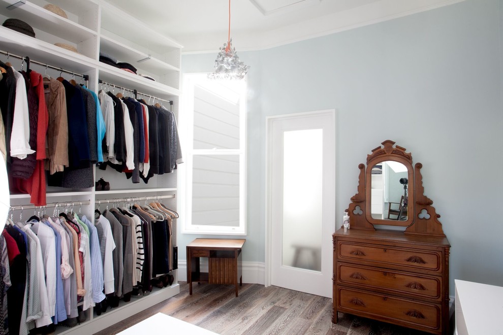 Ejemplo de vestidor actual con armarios abiertos, puertas de armario blancas, suelo de madera en tonos medios y suelo marrón