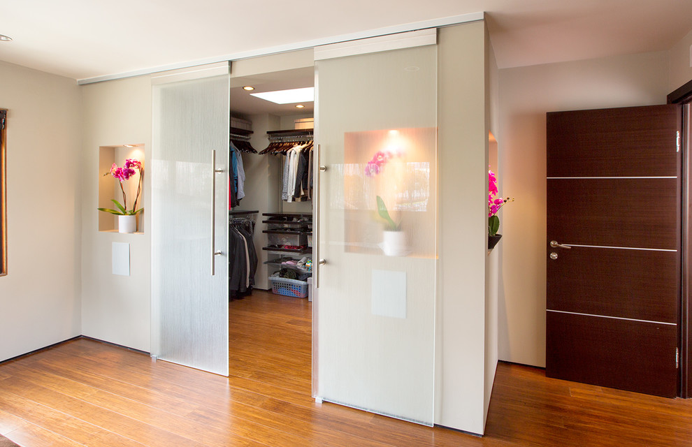Cette photo montre un grand dressing room tendance en bois foncé neutre avec un placard sans porte et un sol en bois brun.