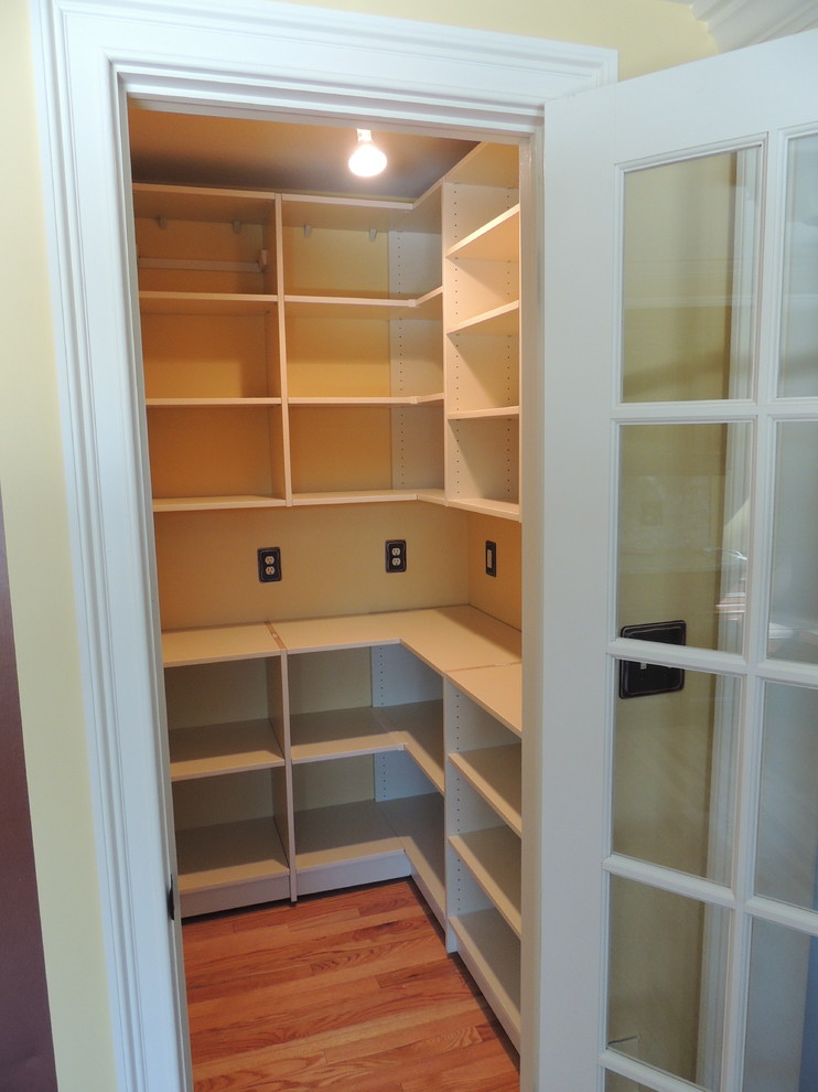 Photo of a medium sized classic walk-in wardrobe in Philadelphia with beige cabinets and light hardwood flooring.