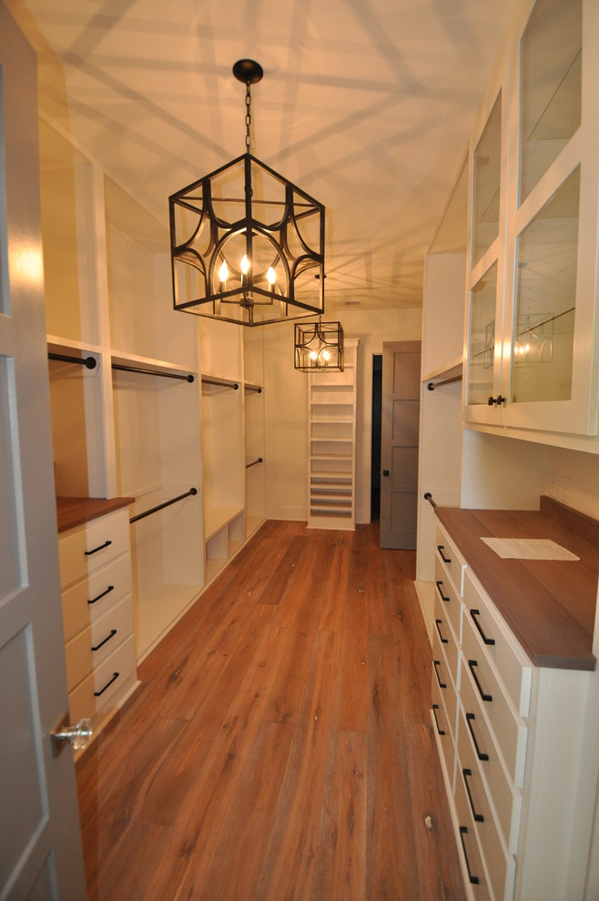 Foto de armario vestidor unisex tradicional renovado grande con armarios con paneles lisos, puertas de armario blancas y suelo de madera en tonos medios