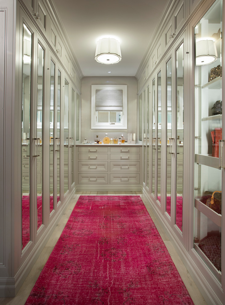 This is an example of a traditional walk-in wardrobe for women in Phoenix with recessed-panel cabinets, beige cabinets and pink floors.