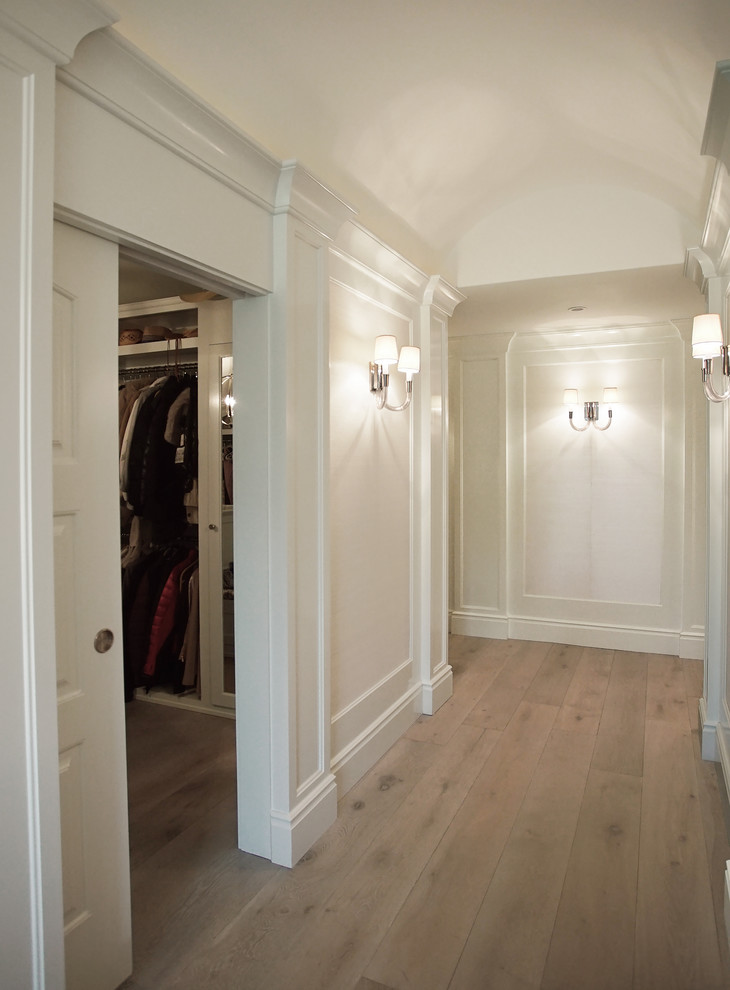 Inredning av ett klassiskt stort walk-in-closet, med luckor med infälld panel, vita skåp, ljust trägolv och beiget golv