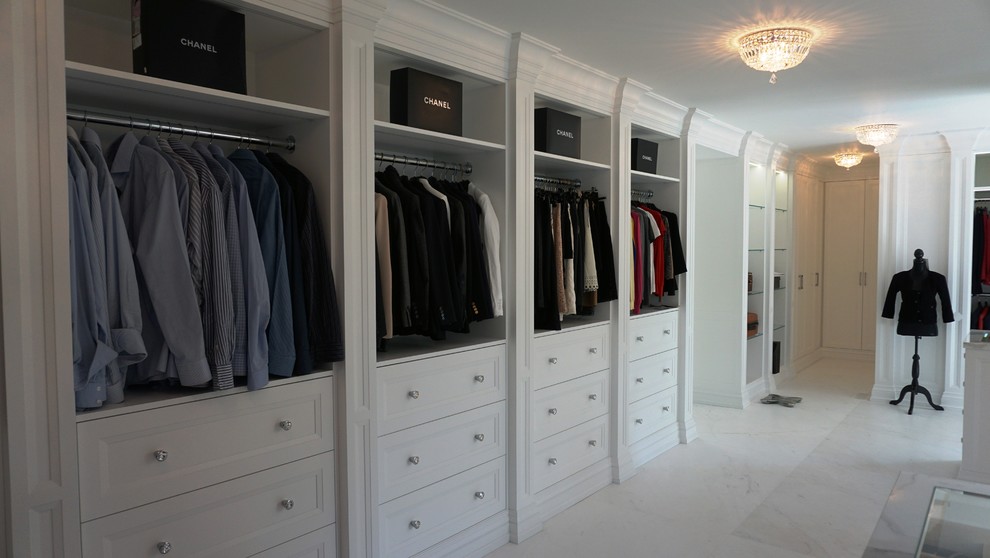 Diseño de vestidor clásico renovado extra grande con armarios con paneles empotrados, puertas de armario blancas y suelo de mármol