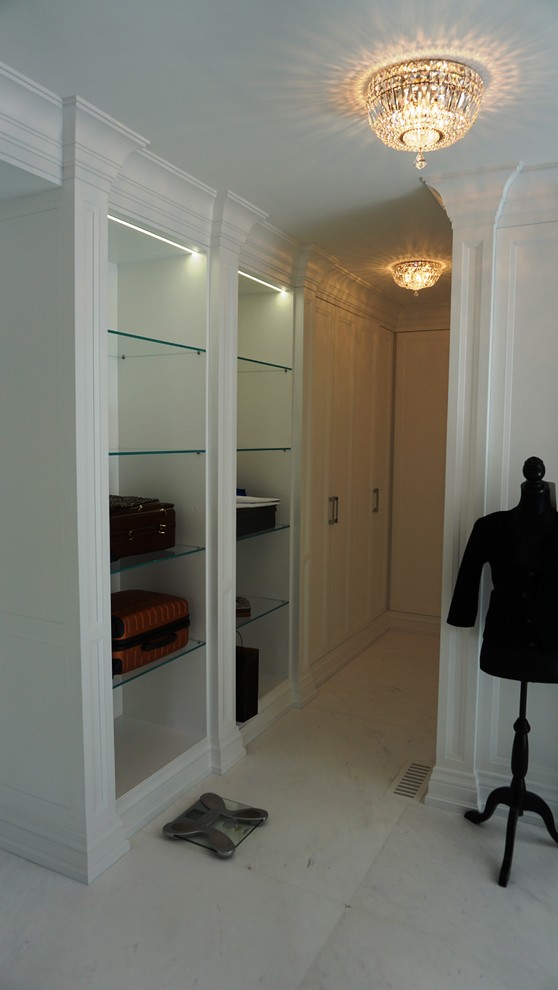 Modelo de vestidor tradicional renovado extra grande con armarios con paneles empotrados, puertas de armario blancas y suelo de mármol