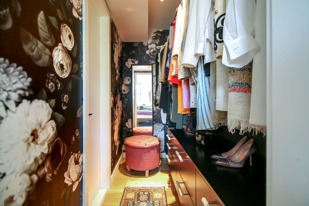 Idéer för små funkis walk-in-closets för kvinnor, med släta luckor, svarta skåp, ljust trägolv och brunt golv